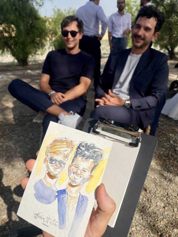 Dos invitados con el retrato en acuarela que acaba de pintarles Alberto Jurada