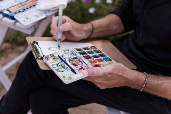 Alberto Jurada pintando en acuarela el retrato de un invitado, con la paleta en la mano