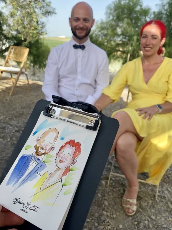 Pareja de invitados con su retrato en acuarela recién terminado