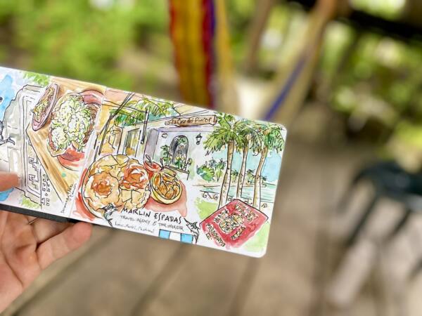 Cuaderno de viaje abierto con platos de comida y palmeras dibujados en Chetumal, México