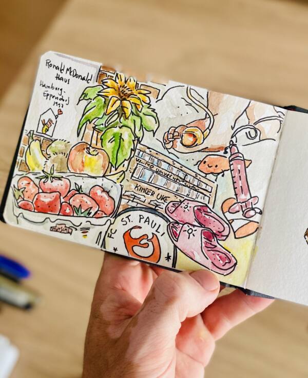 Cuaderno en la mano con el resumen en acuarela de la visita al hospital UKE de Hamburgo