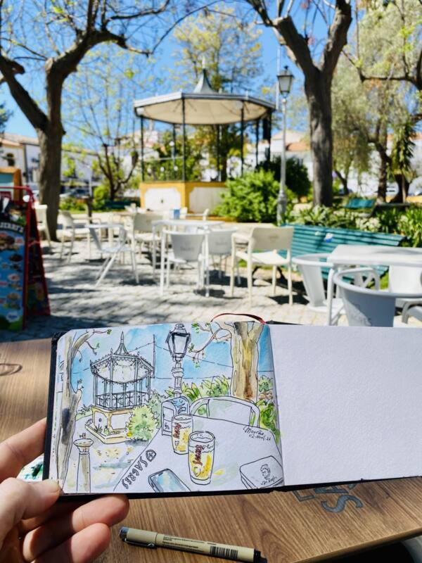 Cuaderno con el dibujo del quiosco de la plaza de Mourão, Portugal, sobre la mesa de una terraza