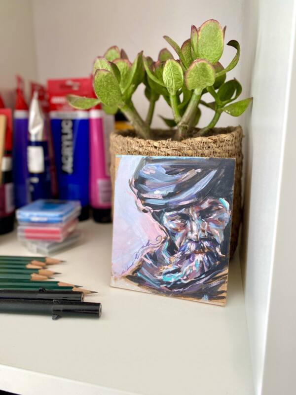 Rincón del estudio con una planta, lápices y un pequeño retrato pintado