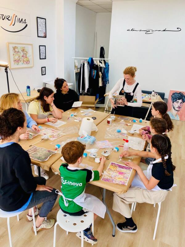 Taller en la mesa grande del estudio Dibujo Libre, con niños y adultos trabajando