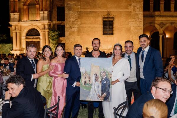 Novios e invitados posando con el cuadro pintado en directo en su boda