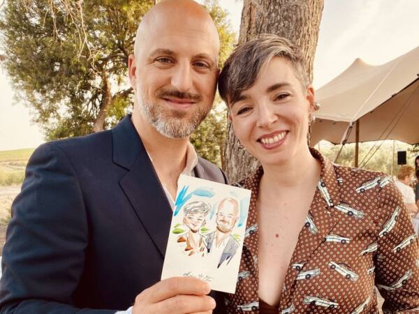 Pareja de invitados de una boda con el retrato en acuarela que Alberto Jurada les ha pintado en directo