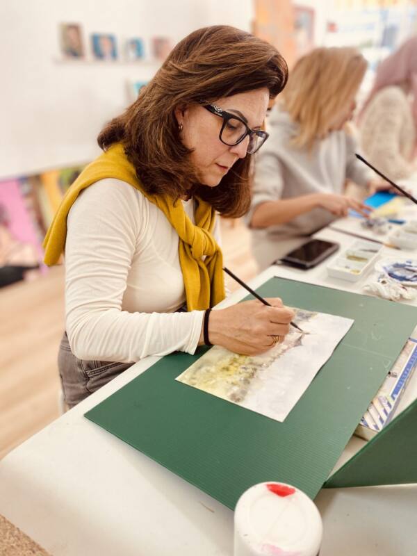 Alumna pintando con pincel fino en la masterclass de acuarela