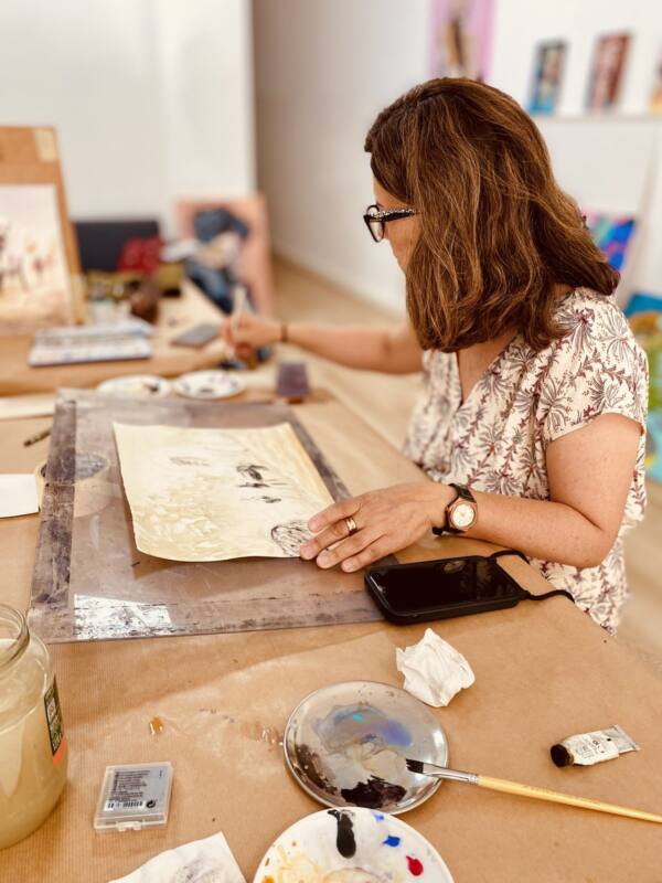 Alumna trabajando una acuarela sobre la mesa del taller