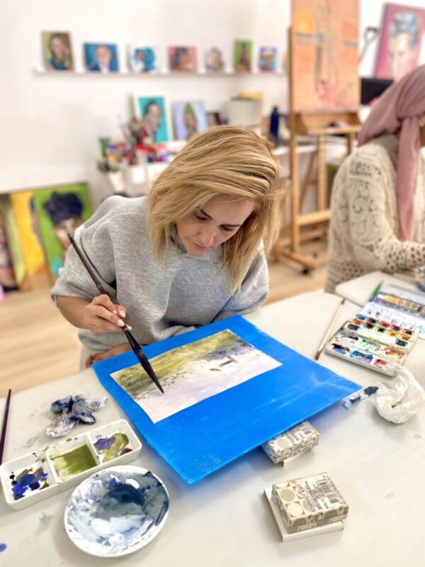 Alumna concentrada pintando una acuarela sobre tabla azul