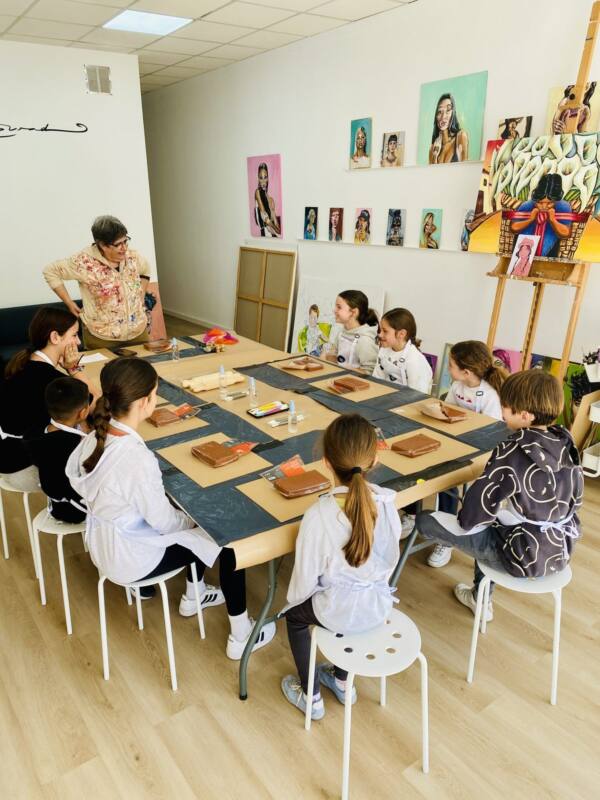 Niños trabajando el barro alrededor de la mesa del estudio