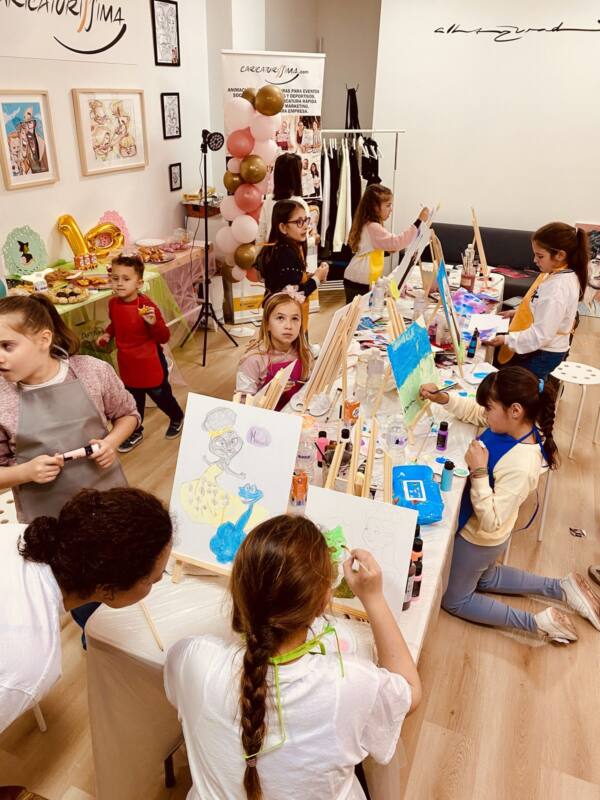 Niñas pintando en caballetes durante un taller infantil en el estudio