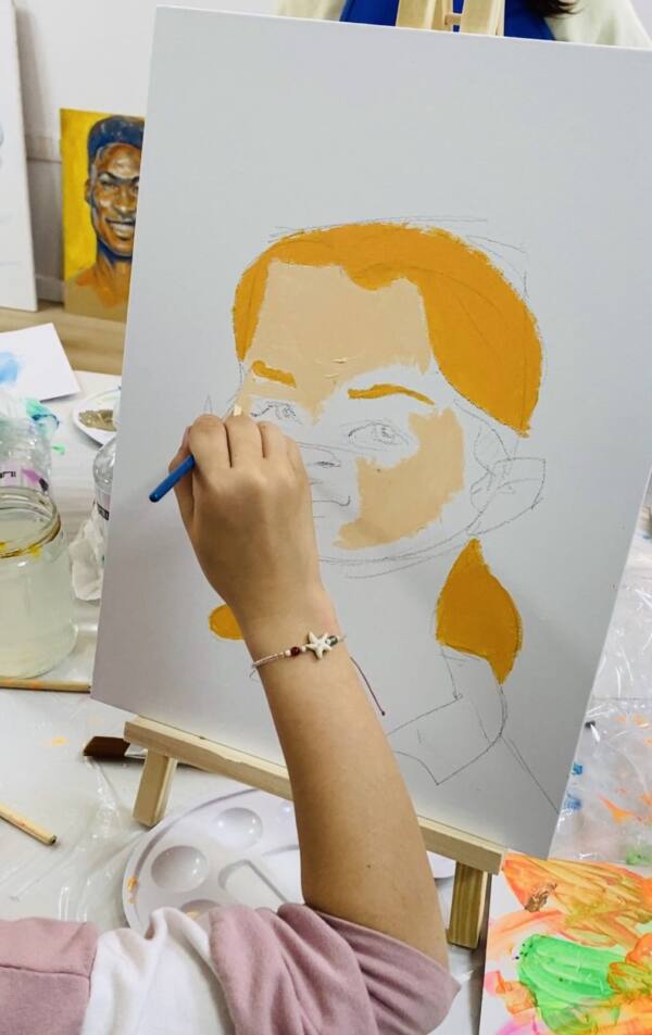 Mano pintando un retrato en un lienzo durante un taller de retrato